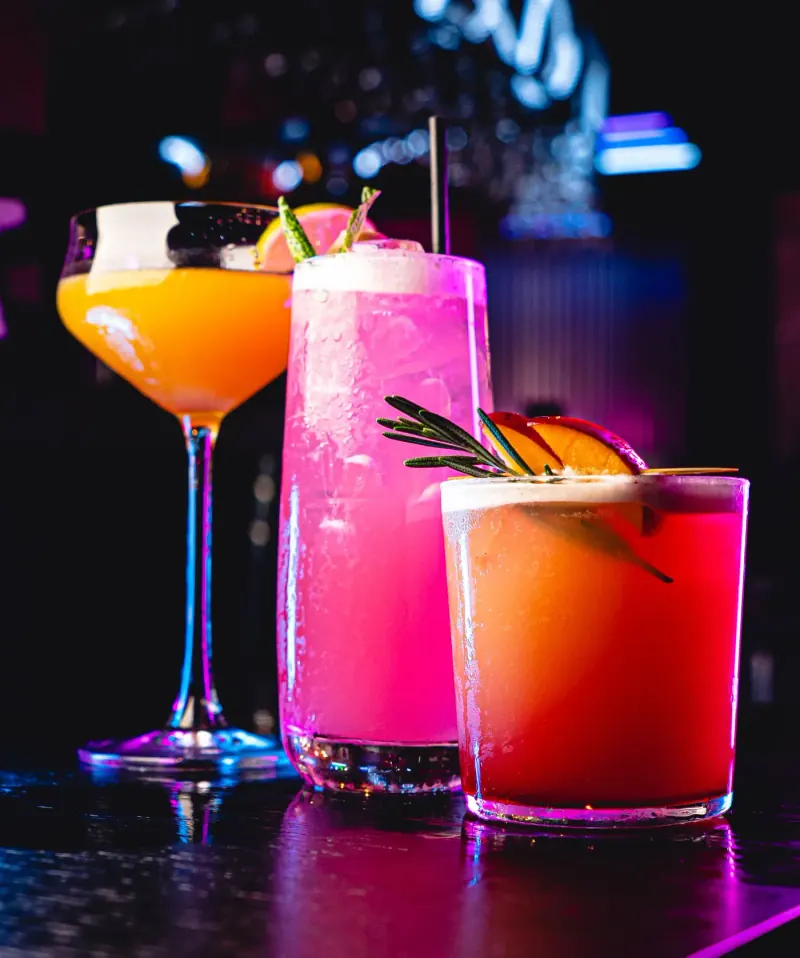 Three signature cocktails - pink, peach and citrus - on the bar at Seafood City Birmingham